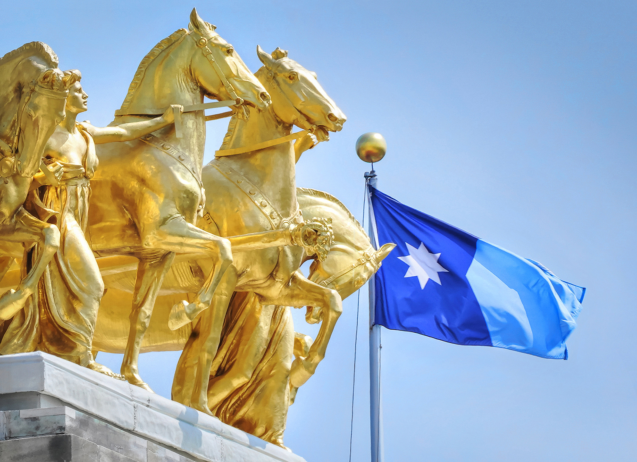 The Minnesota State flag flies with the Quadriga.